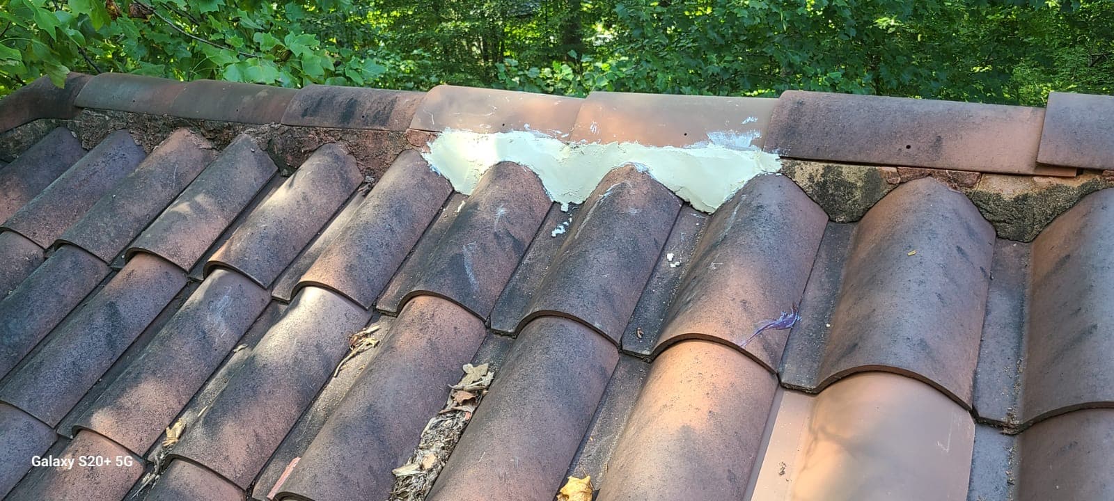 Close view of Spanish clay tile roof repair along a ridge line